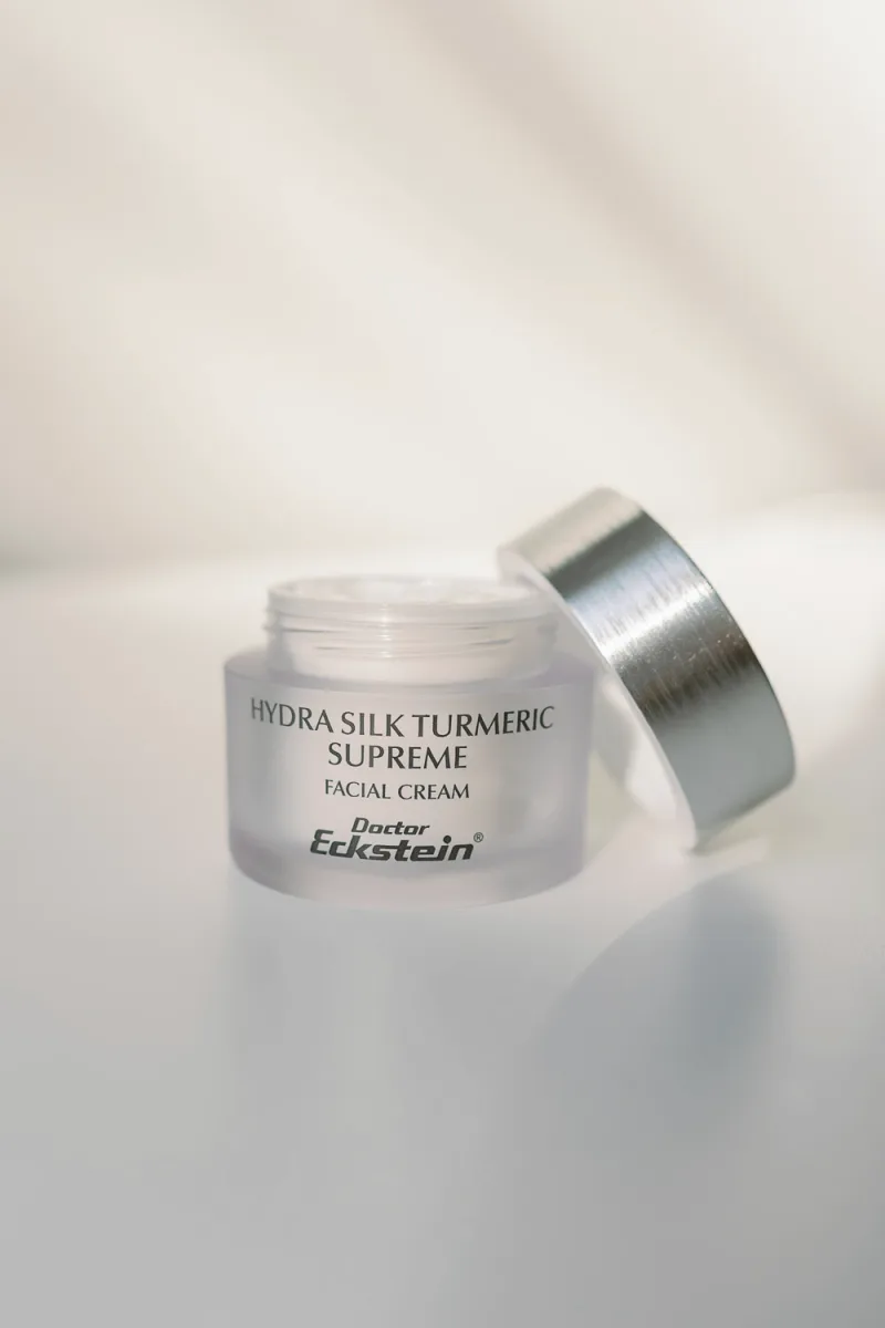 Glass jar facial cream with silver lid on neutral background, product shot