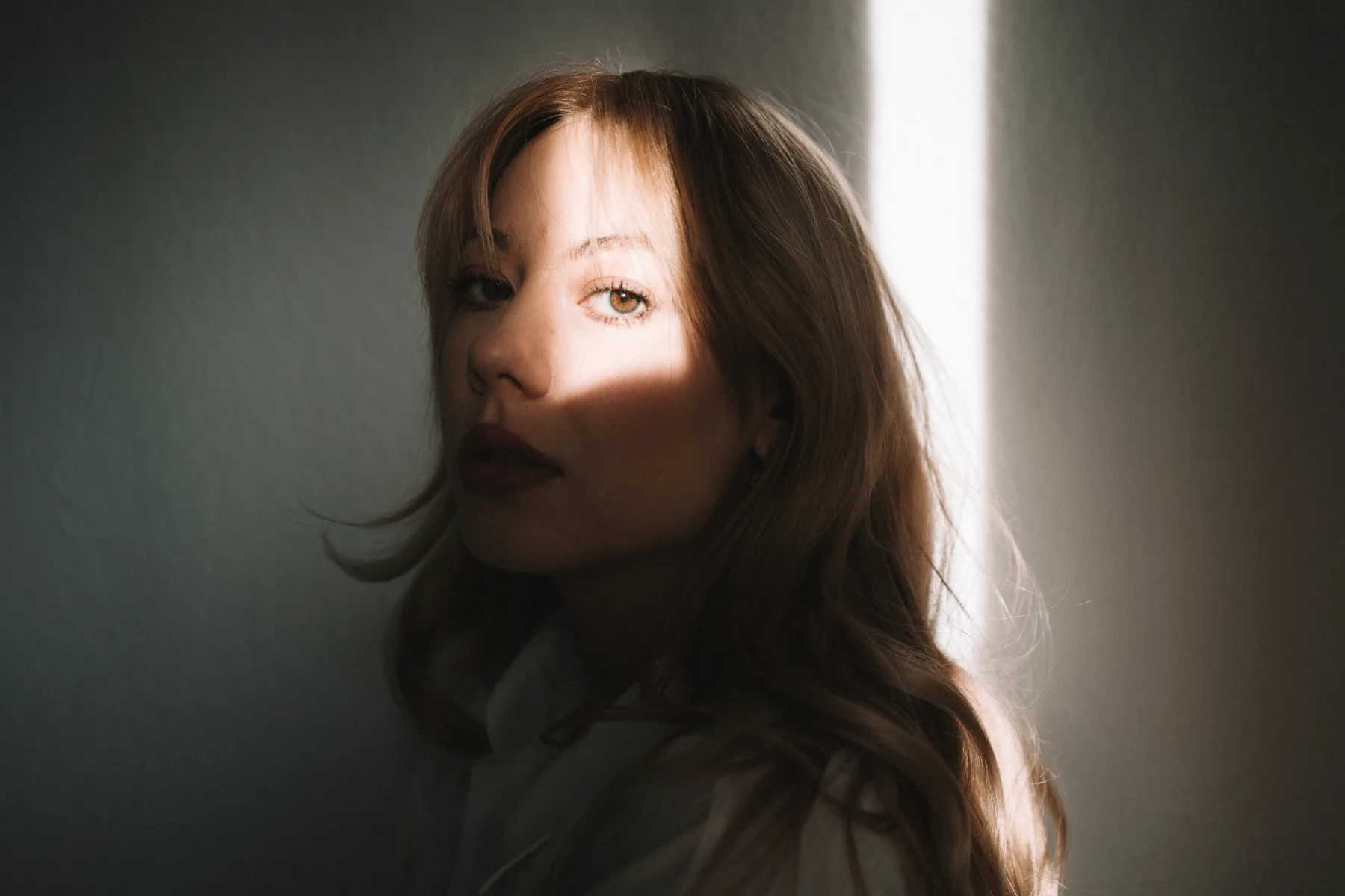 Woman with long dark hair in profile portrait with warm side lighting glowing