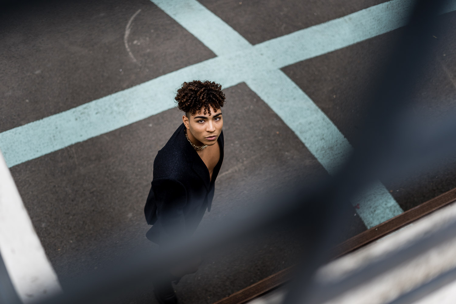 Woman with curly dark hair in black outfit on ground with geometric lines