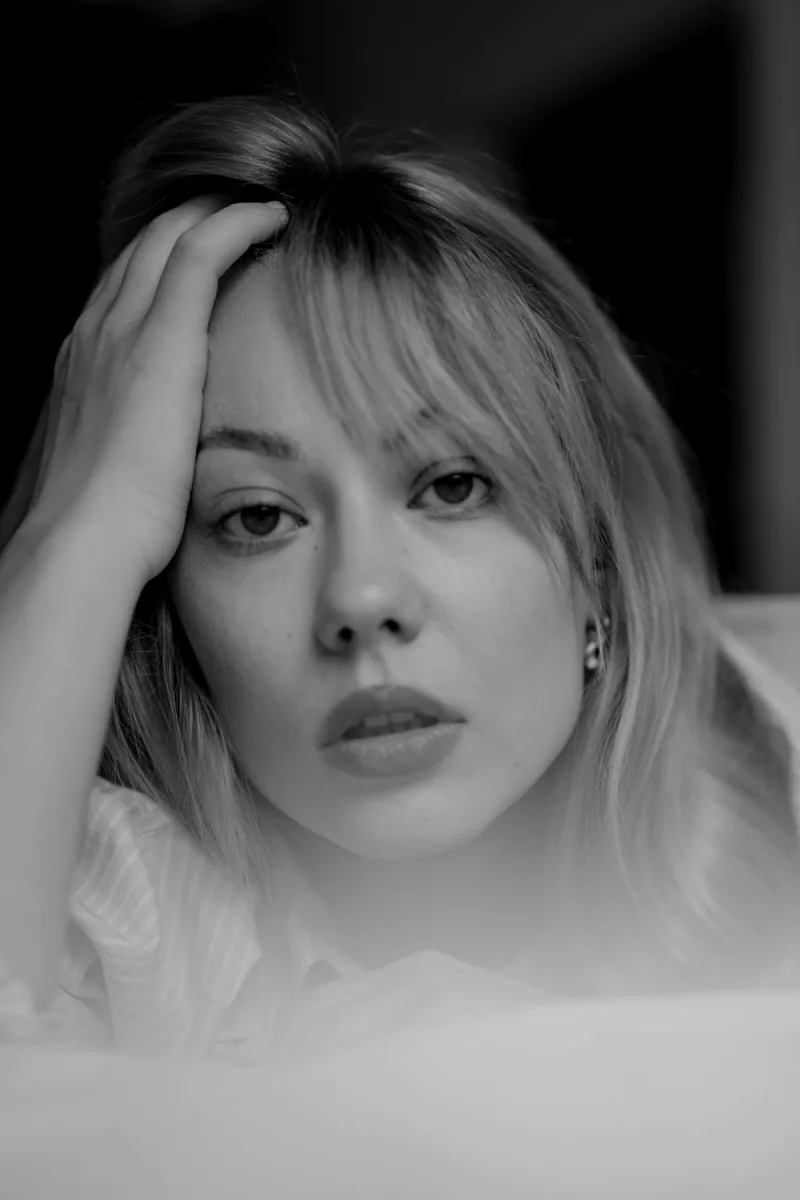 Woman in black and white portrait hand near face with bangs and soft gaze