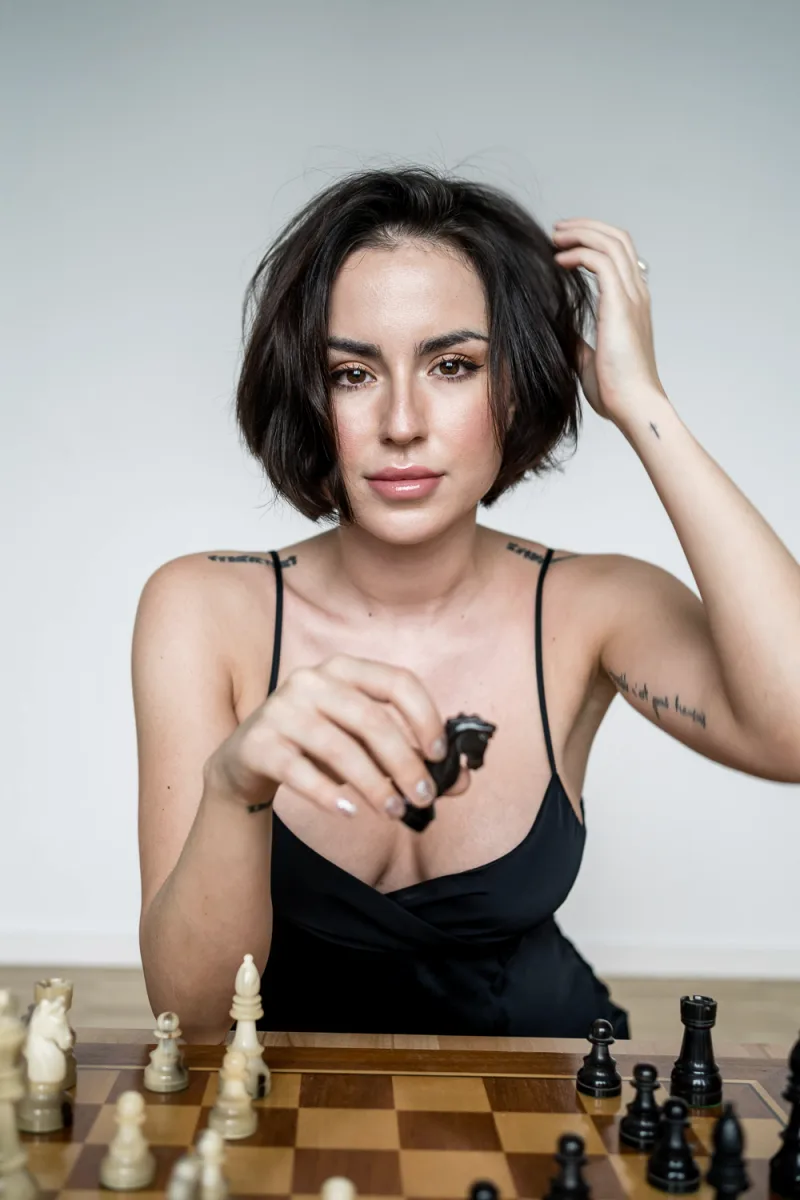 Woman with short black bob hairstyle in black top playing chess