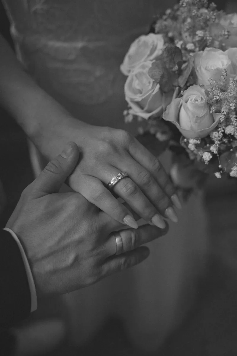 Bride and groom displaying wedding flowers with rings visible on their hands
