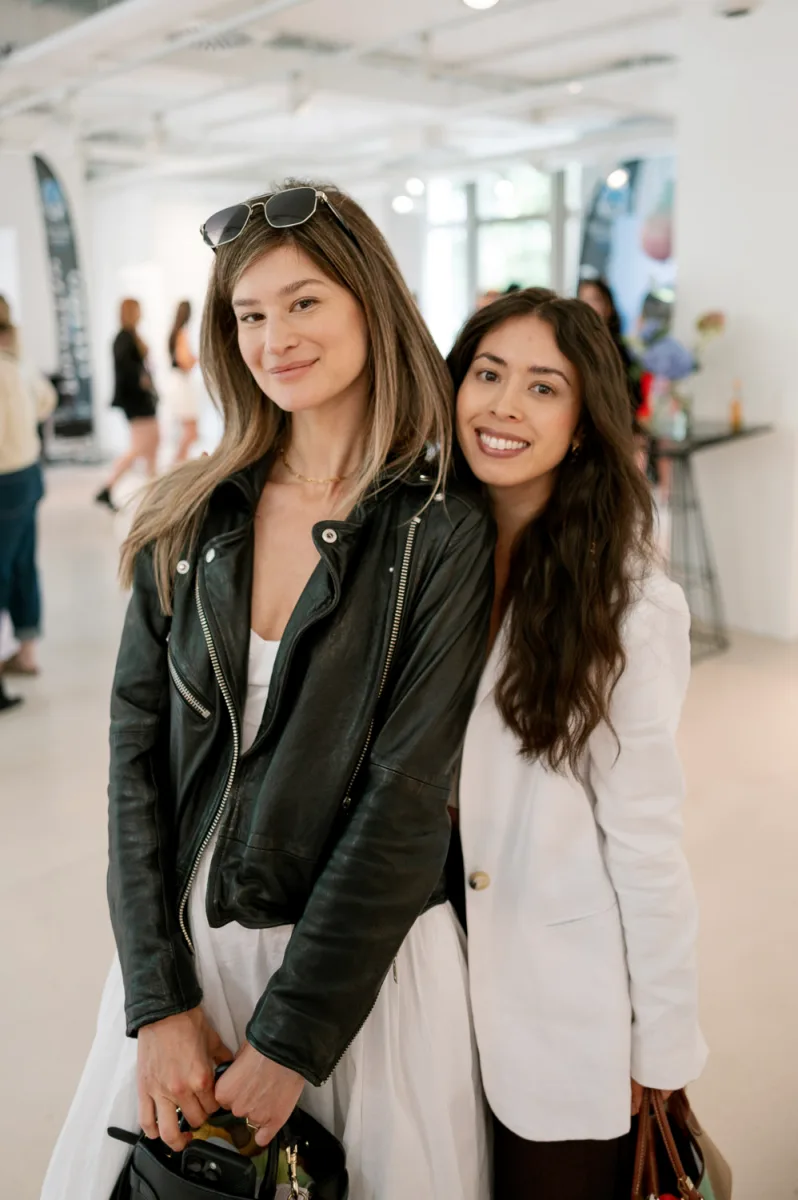 Two women smiling at modern gallery venue in leather jackets, casual contemporary