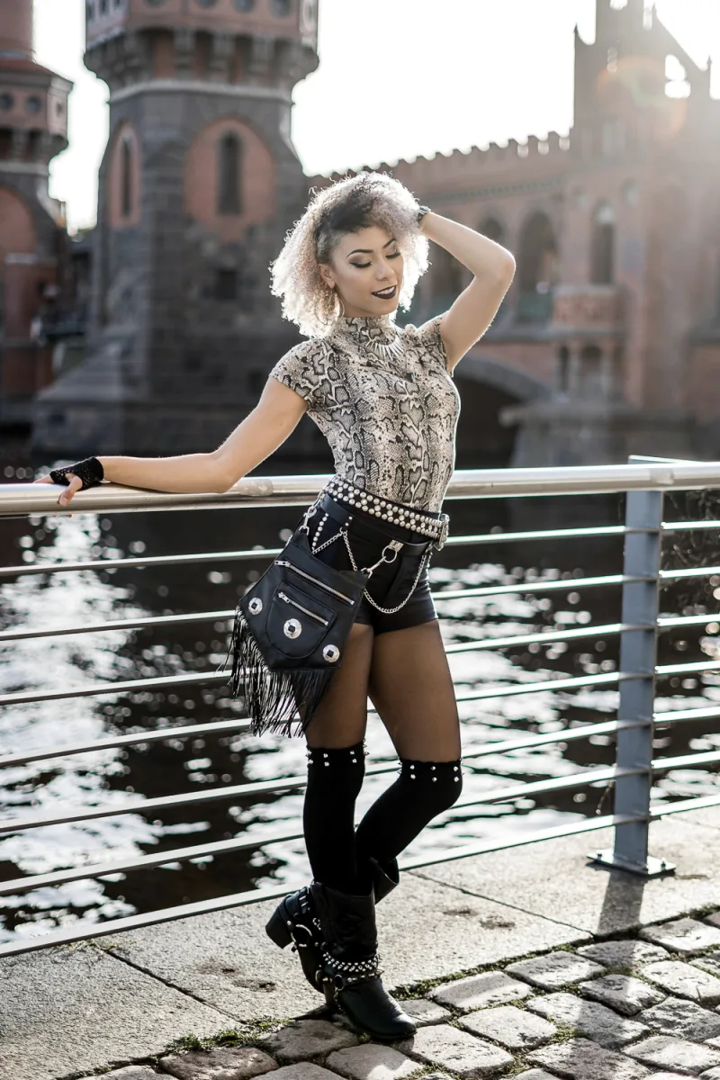 Woman with curly white hair in python patterned top and studded boots