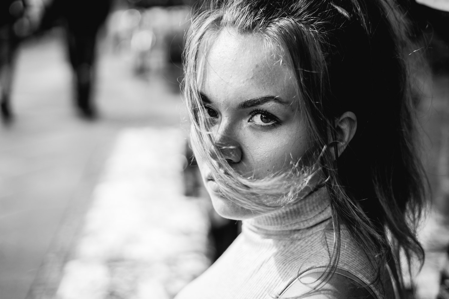 Woman with hair across her face looking downward in soft focus black and white portrait