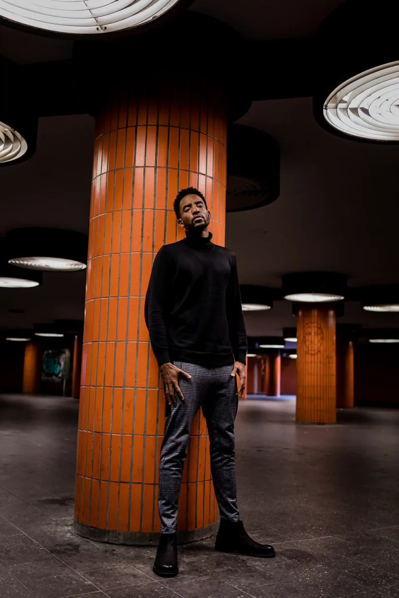 Man standing at yellow U-train platform, incoming train with amber and blue lighting