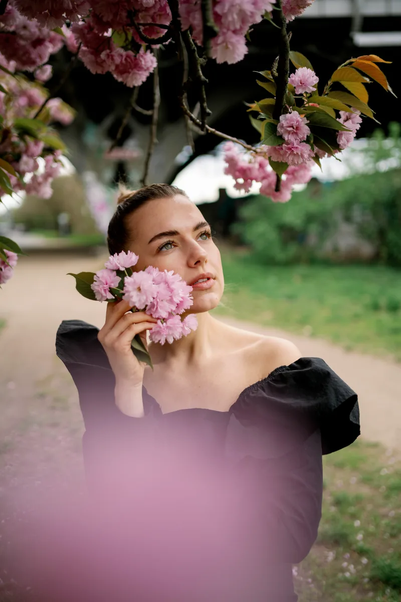 Woman in pink dress holding pink flowers with blurred garden backdrop