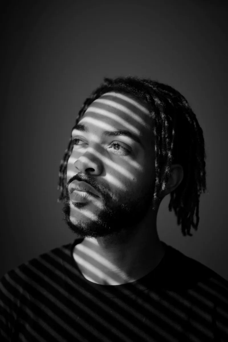 Man with dreadlocks in black and white portrait with horizontal light stripes