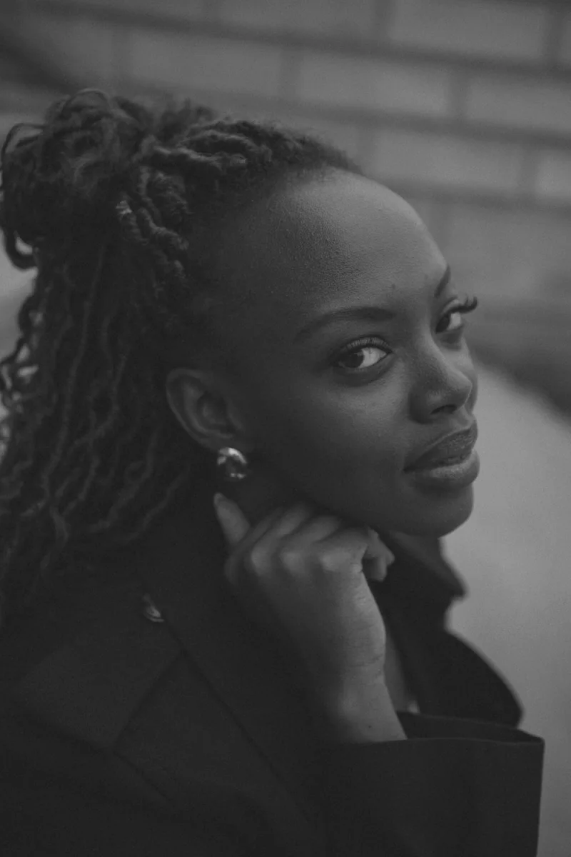 Woman with dark braided hair in side profile, neutral expression, pearl earrings