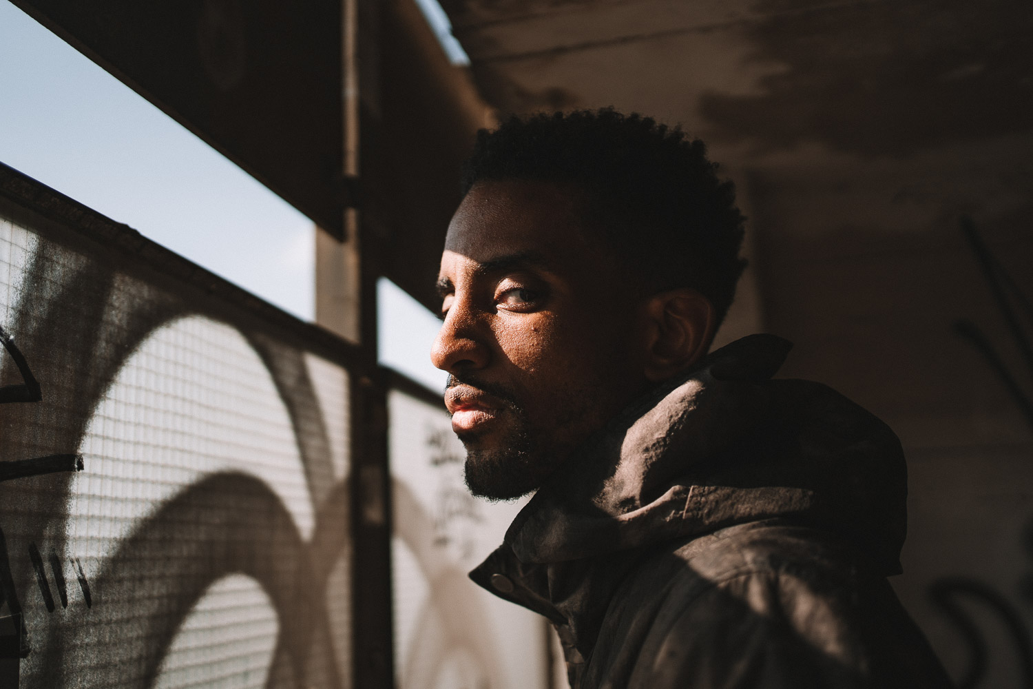 Man with dark beard and warm golden light from window blinds